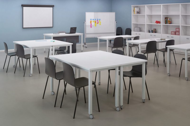 Aula de formación con mesas, sillas y pizarra móvil